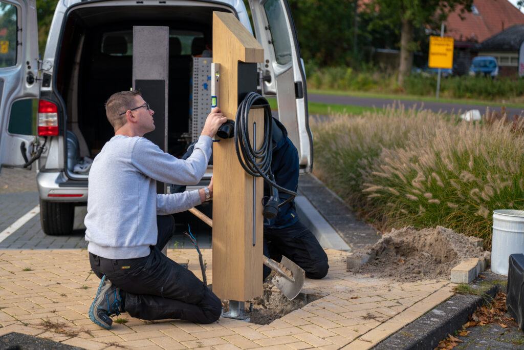 Monteur bezig met laadpaal installatie op een oprit van een woning